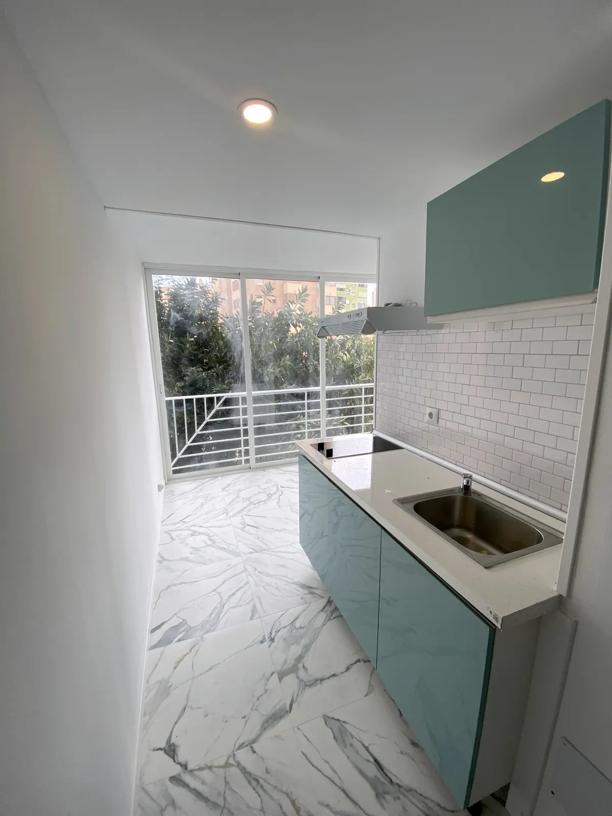 Bespoke kitchenette and marble-effect floor in a renovated studio